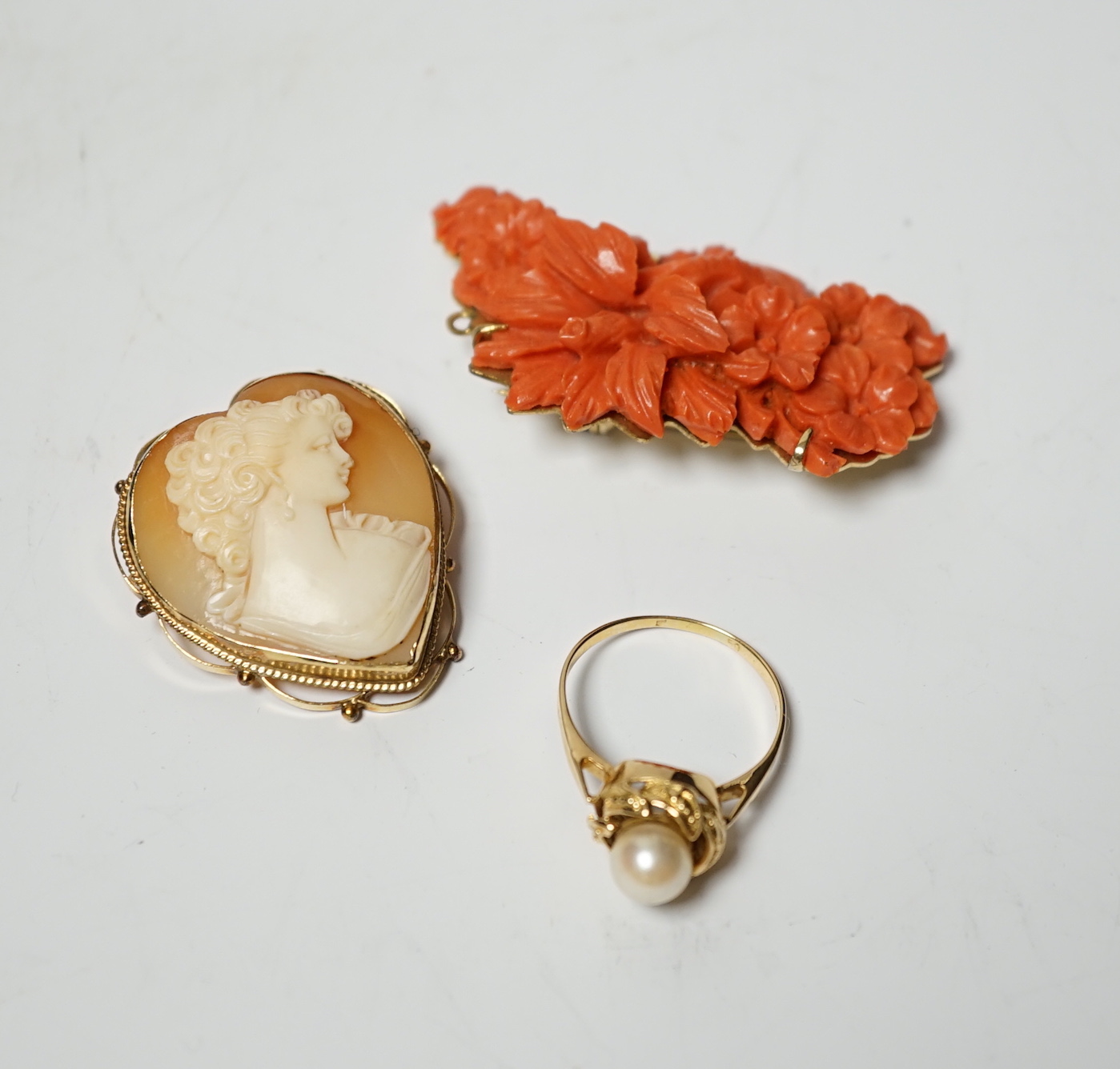 A 14k mounted heart shaped cameo shell pendant brooch, 33mm, a yellow metal and single stone cultured pearl set ring and a coral brooch.